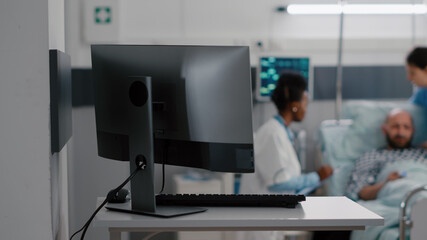 Afro american practitioner doctor discussing recovery treatment with sick man writing medical expertise on clipboard while nurse arrange bed. Hospitalized patient having respiratory disorder