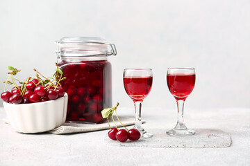 Glasses of sweet cherry wine on light background
