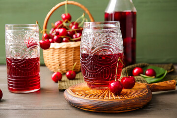 Glasses of sweet cherry wine on wooden table