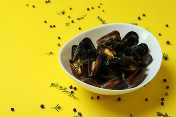 Bowl with fresh mussels on yellow background