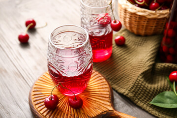 Glasses of sweet cherry wine on wooden background, closeup