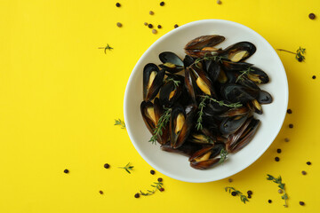 Bowl with fresh mussels on yellow background