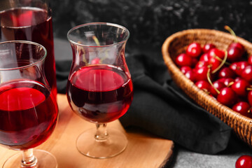 Glasses of sweet cherry wine on table, closeup
