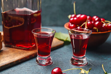 Glasses of sweet cherry wine on color background