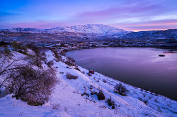 Obraz premium Beautiful winter morning landscape at Lake Ram or Birkat el-Ram, a crater lake (maar) in the northeastern Golan Heights, Israel, surrounded by snow-covered hills