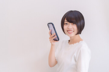 Fototapeta premium スマホを持って嬉しそうにこちらを見る女性
