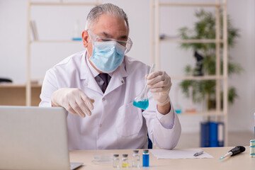 Old male chemist working in the lab during pandemic