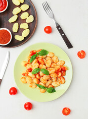 Plate with tasty gnocchi on light background