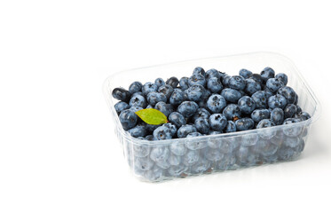 Fresh organic blueberries in a transparent plastic tray. Dark blue ripe  fruits of Vaccinium corymbosum. Close-up, isolated on white. Copy space