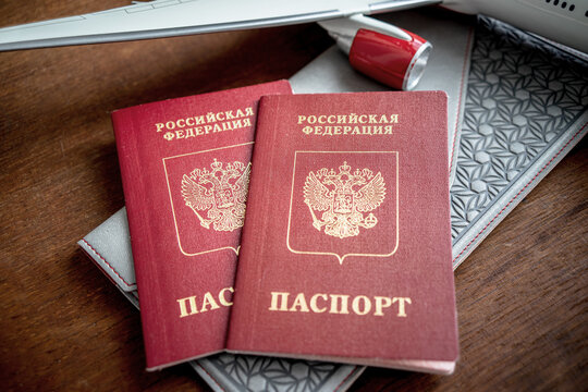 Two red Russian foreign passports and a wing of a model aircraft. Preparation of documents for vacation.