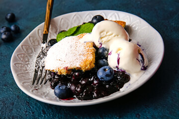 Plate with pieces of blueberry cobbler and ice cream on dark background, closeup
