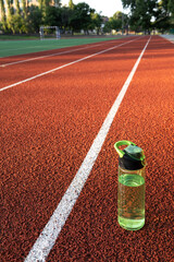 Vertical image of red sunning road and bottle water on the stadium