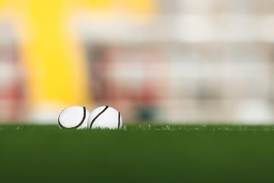 Two size 5 official hurling championship sliotars lie in the grass with an out of focus background with copy space