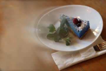Man's hand revealing a slice of raw vegan cake under a glass bell