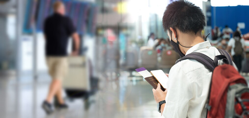 Man with backpack and hand luggage walking in airport terminal  travel and vacation concept.