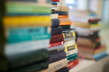 A pile of old library books standing on top of each other on a home bookshelf
