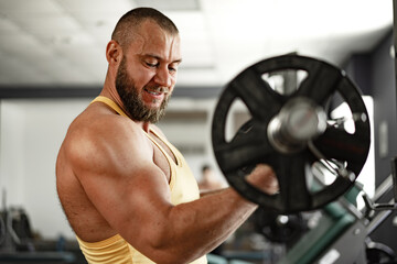 Strong bodybuilder with muscular chest and shoulders in gym