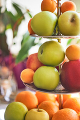 Three tier fruit bowl, tray stand, holding many apples, oranges and peaches waiting to be eaten