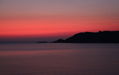 Fototapeta premium warm tones of a fiery sunset with the island and the sea without people