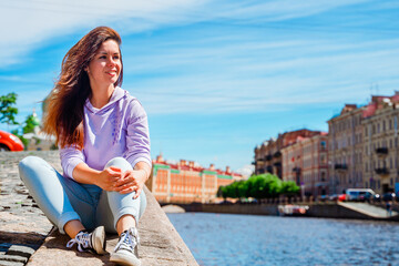 Fototapeta na wymiar A young woman walks along the embankment in St. Petersburg with beautiful views of bridges and canals.
