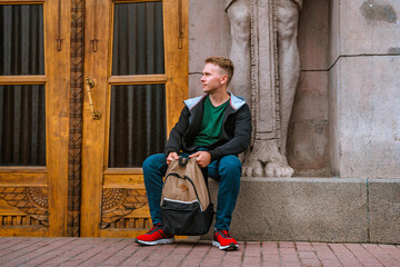 A young man sits near the entrance to an Egyptian house in the center of St. Petersburg