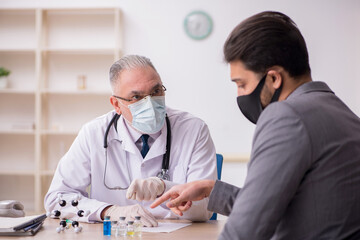 Young businessman visiting old male doctor in vaccination concep