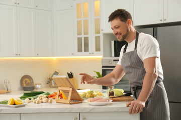 Man watching online cooking course via tablet in kitchen