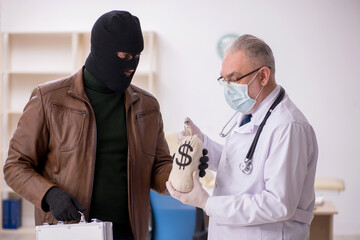 Masked man burglar bribing old doctor for getting vaccine