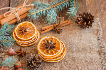 Christmas tree branch with dried oranges, cinnamon, nuts and anise star on wooden table
