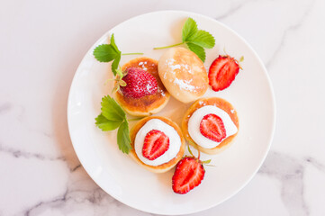 Delicious morning breakfast. Cheese pancake. Curd pancakes beautifully decorated with strawberry slices and sour cream.