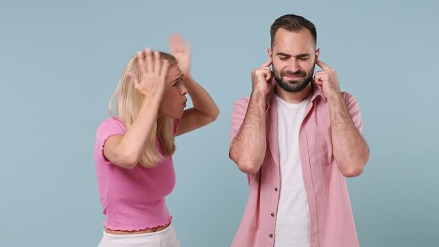 Young couple two friends family in pink clothes together man closes ears with hands says blah blah woman scream scolding swearing isolated on pastel plain light blue color background studio portrait