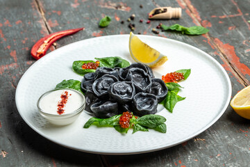 Black dumplings stuffed with fish and caviar. ravioli, dumplings. Russian cuisine. banner, menu, recipe place for text, top view