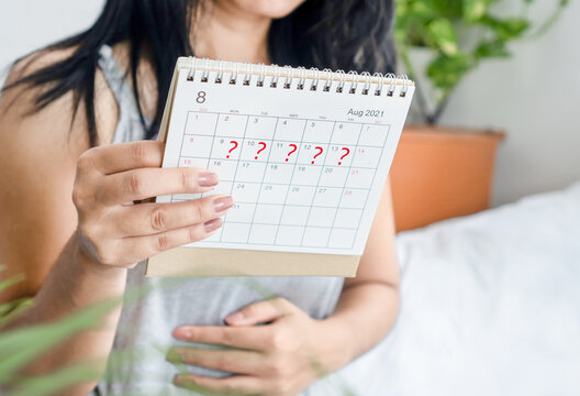 woman hand holding calendar with question mark waiting for late blood period, amenorrhea, irregular periods concept