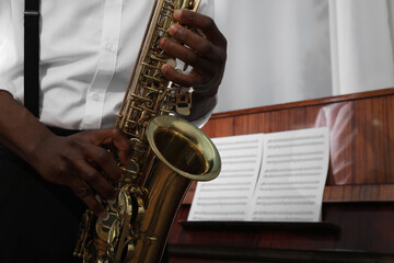 Obraz premium African-American man playing saxophone indoors, closeup with space for text. Talented musician