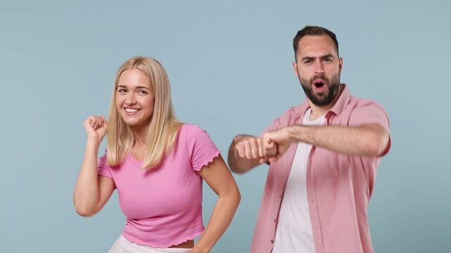 Young couple two friends family man woman in pink clothes together dancing have fun expressive gesticulate hands show victory sign isolated on pastel plain light blue color background studio portrait