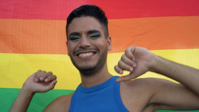 Happy homosexual man celebrating gay pride with rainbow flag symbol of LGBTQ community