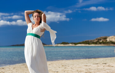 Fototapeta na wymiar Woman on Sunny Sea Beach in White Fluttering Dress, Elafonissi Grece 