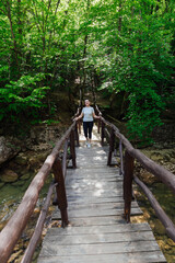 woman walking across a bridge in a green forest travel hike
