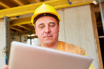 Bauarbeiter als Vorarbeiter schaut auf Tablet Computer