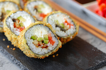 Japanese sushi tempura roll served on black stone plate