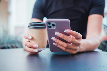 Young girl using smartphone in hand, drinking coffee