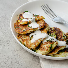 Vegetable pancakes on a white plate in a bright, atmospheric interior,close up.