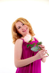 Happy beautiful woman with long blond curly hair and in elegant dress posing with rose flower in studio on white background