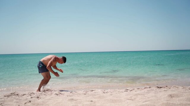 Athletic man doing back flip on the sea beach. Summer vacation concept. Slow motion.