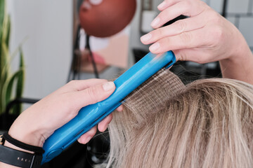 Corrugated hair straightener while adding texture and volume to hair. A woman makes herself...