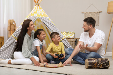 Happy family with treasure map near toy wigwam at home © New Africa