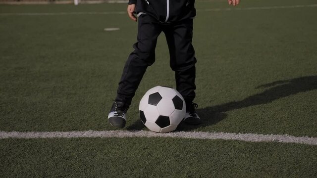 Closeup of little boy soccer player trains on a soccer field with green grass