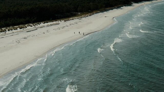 Aerial beautiful beach at the Polish seaside, waves are hitting the shore, a small group of tourists is walking along the shore, Stilo Beach, Poland