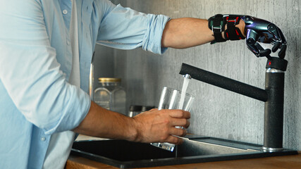 Male person with black artificial hand prothesis pours water into transparent glass from large bowl...