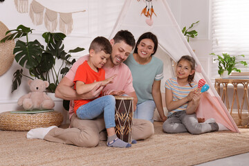Happy family playing together near toy wigwam at home © New Africa